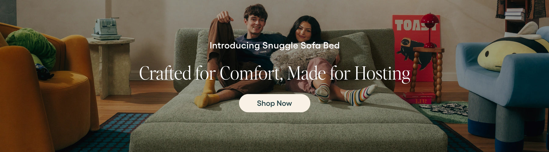 Two people sitting on a couch with promotional text for 'Snuggle Safe Bed' in a living room setting.