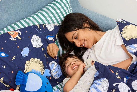 Woman and child lying on a bed with space-themed bedding