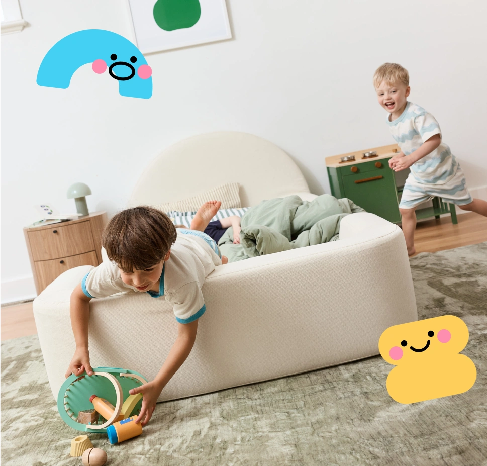 Children playing with toys on a couch in a room with a colorful character sticker.